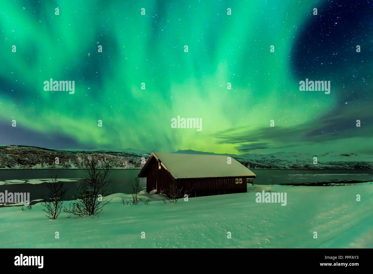 Northern Lights aurores boréales dans la nuit au-dessus d'une maison de style typiquement artic comté de Troms, Norvège. Le ciel est un peu brouillé le paysage Banque D'Images