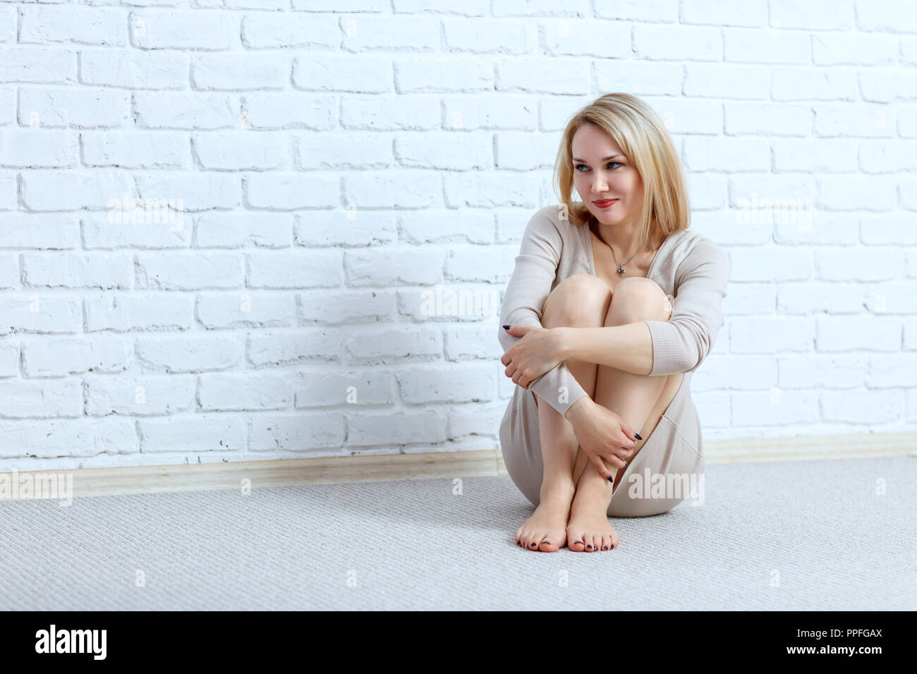 Belle femme assise sur le sol plus de mur arrière-plan. Banque D'Images