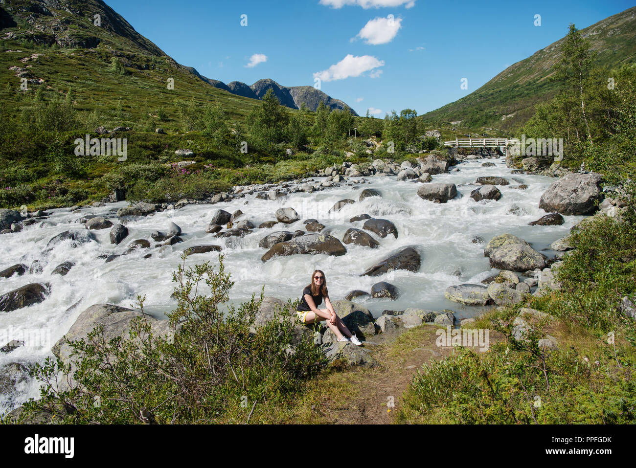 Randonneur assis près de la rivière de montagne sur Besseggen Ridge dans le parc national de Jotunheimen, Norvège Banque D'Images