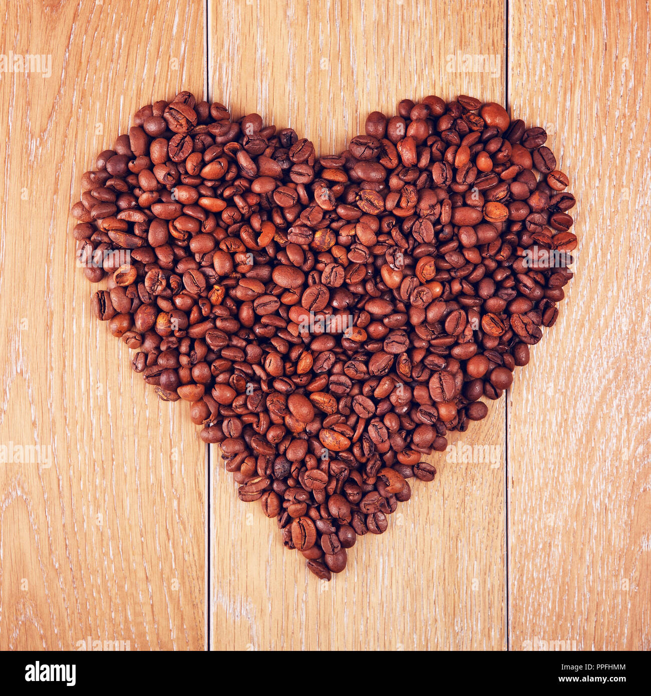 Café en grains en forme de coeur sur table en bois, l'arrière-plan Banque D'Images