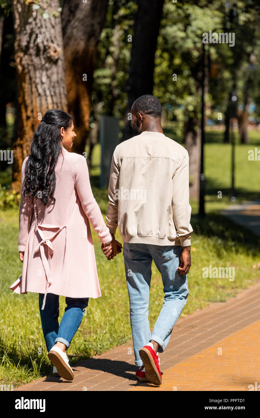 Vue arrière de l'african american couple holding hands and walking in park Banque D'Images
