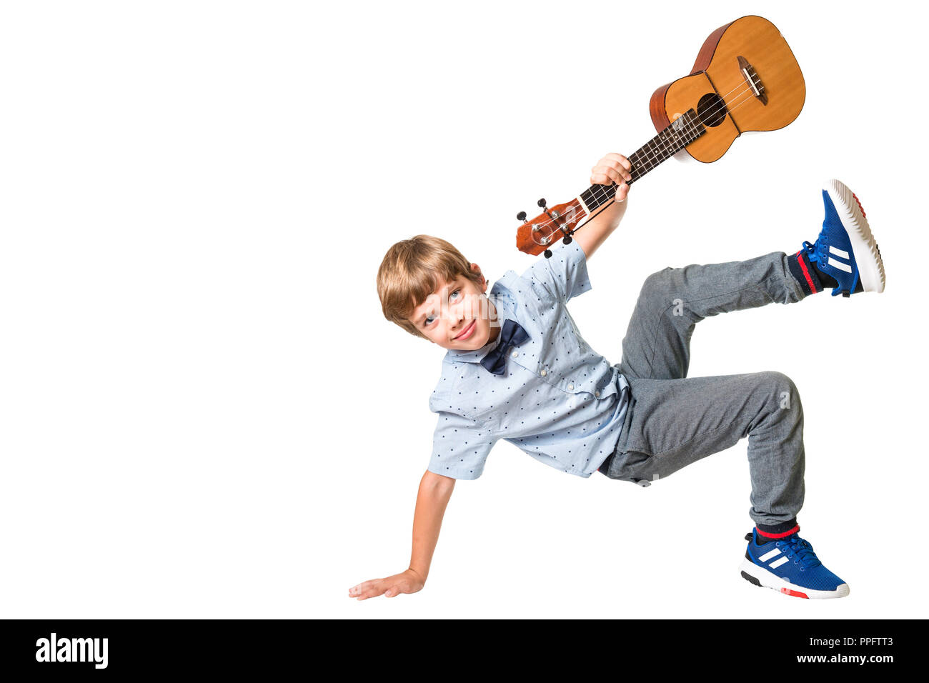 Adorable jeune garçon posant avec ukulele dans sa main, isolé sur fond blanc avec un espace réservé au texte Banque D'Images