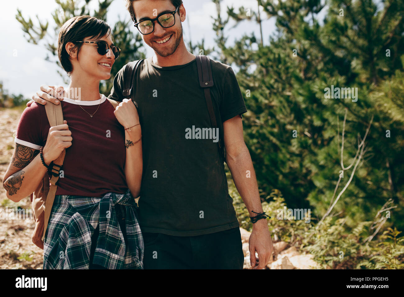 Homme et femme sur une maison de vacances à marcher ensemble dans une forêt. Smiling couple portant des sacs à dos randonnée ensemble. Banque D'Images