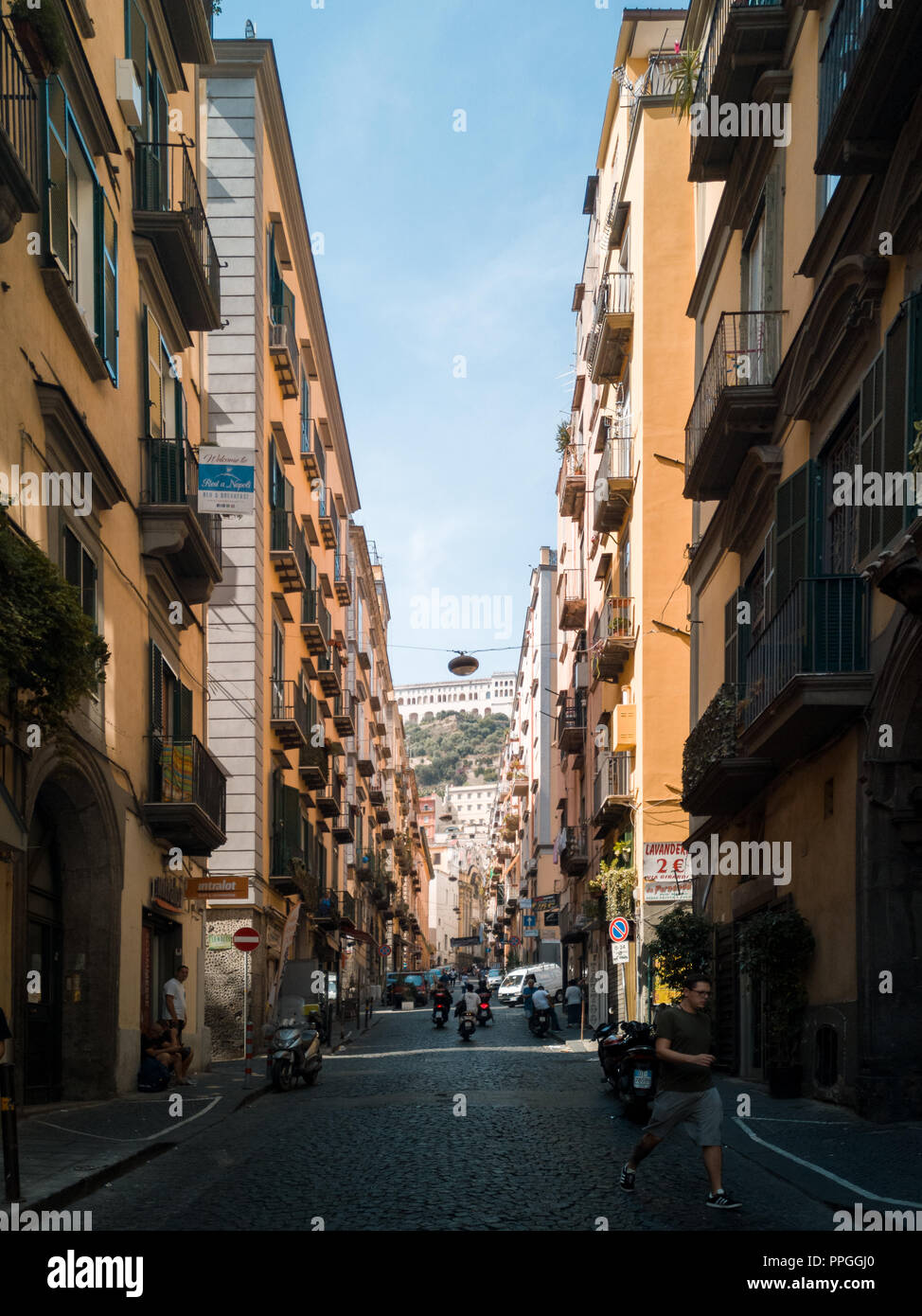 Une rue principale à naples Italie, flanqué d'immeubles d'appartements avec une vue jusqu'à Castel Sant'Elmo forteresse. Banque D'Images