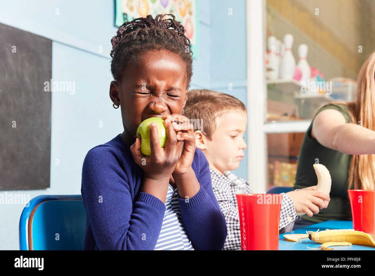 Jeune fille africaine est de manger une pomme en collation collation en maternelle ou à la garderie Banque D'Images