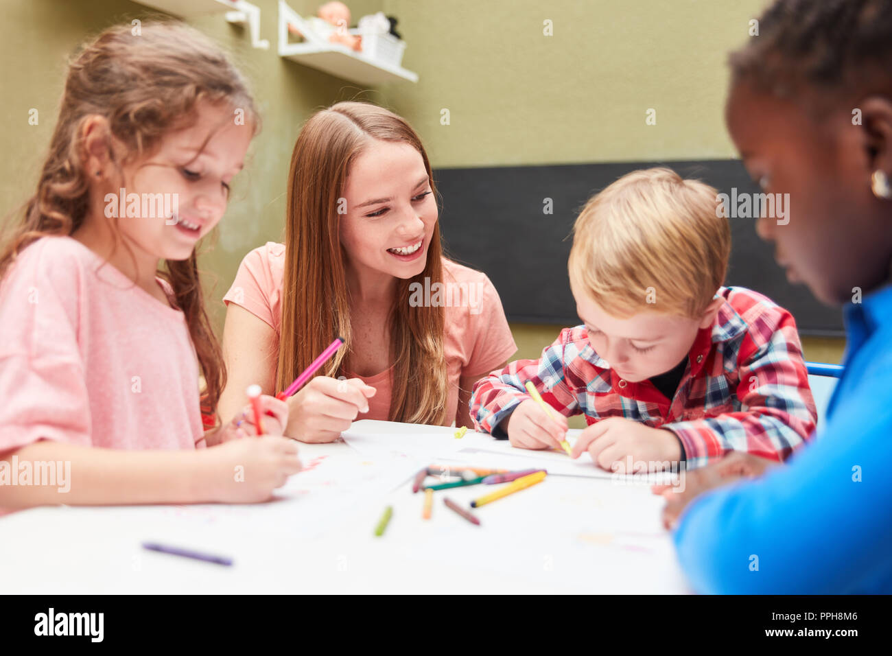 Groupe d'enfants s'amuse en peinture dessin classe ensemble avec l'enseignant d'école maternelle Banque D'Images