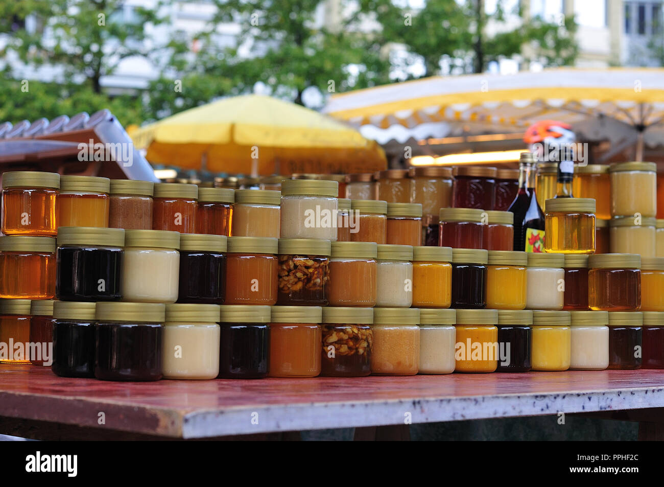 Les contenants de verre avec du miel empilé par stand au marché du marché fermier Banque D'Images