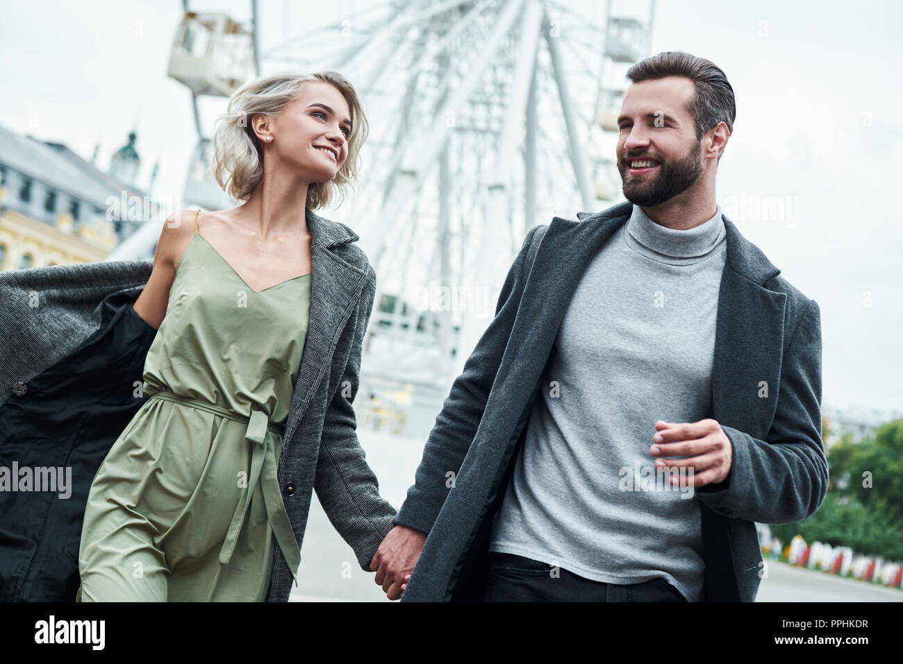 Date romantique en plein air. Jeune couple tournant au parc de divertissements à la main à chaque autre smiling happy close-up Banque D'Images