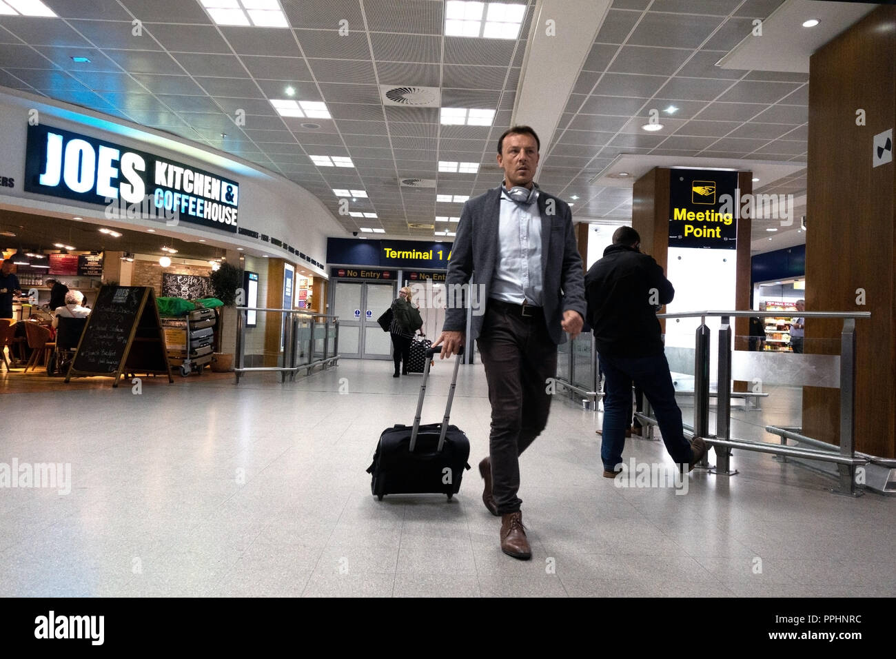 Un passager à pied à travers l'aéroport après leur arrivée à l'Aéroport International de Manchester à T1 : le hall d'arrivée Banque D'Images