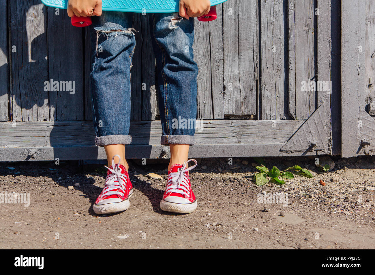 Close up pieds d'une fille en rouge et chaussures de skate board blue penny avec roues rose debout à côté du mur. Scène urbaine, la vie en ville. Sport, Fitness Banque D'Images