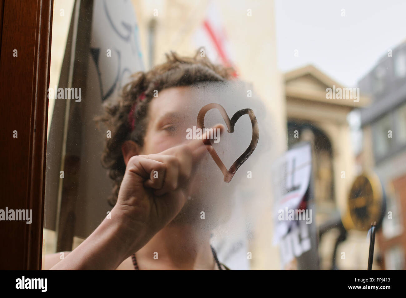 La respiration d'un homme sur une vitrine de verre attire la forme d'un coeur avec son doigt. Banque D'Images