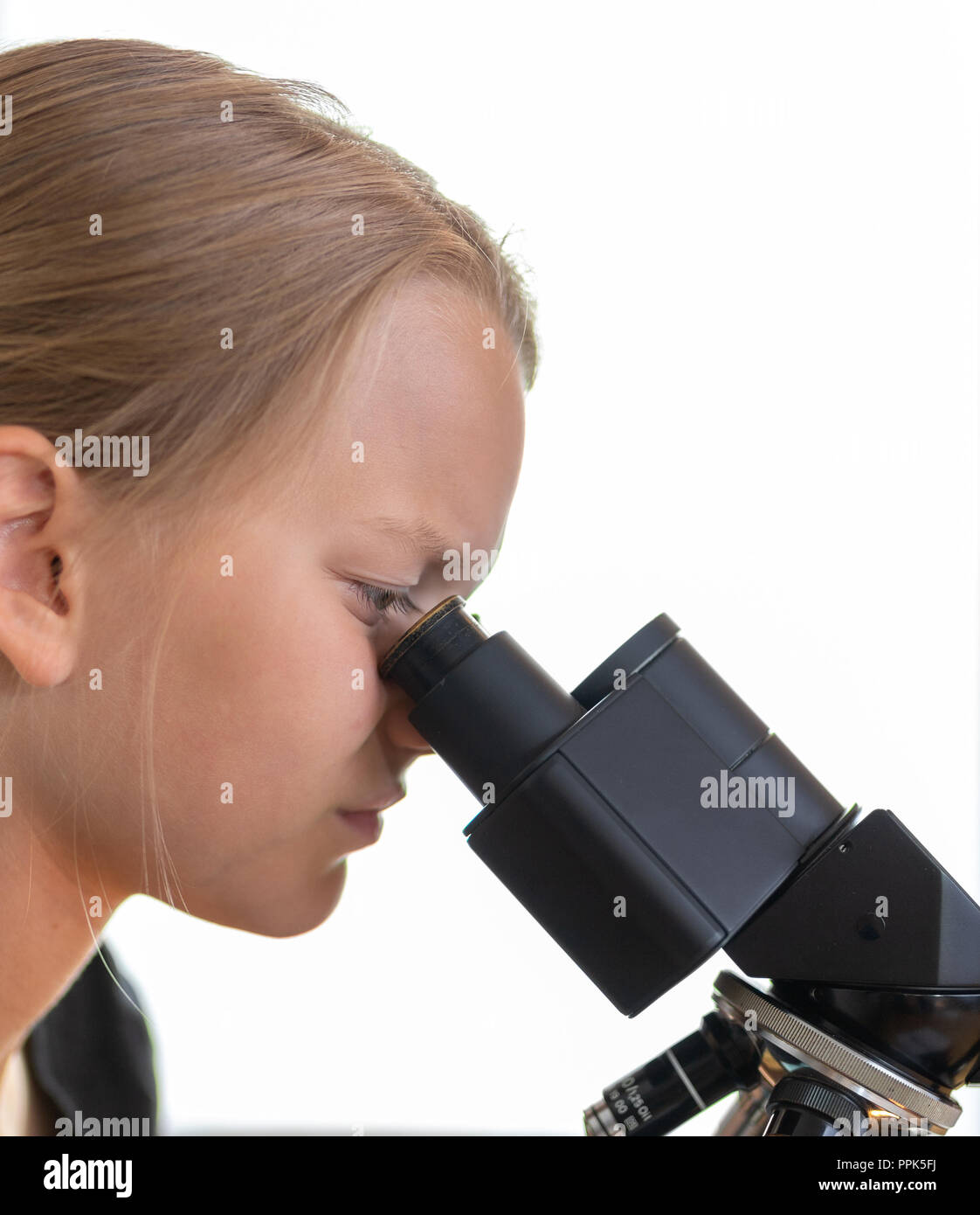 Une fille de 9 ans cherche dans un oculaire d'un microscope. Contre isolé sur fond blanc Banque D'Images