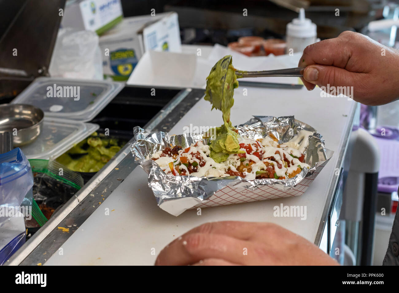 Golden, Colorado - Adam Hjermstad guacamole ajoute à un plat dans son feu dans la berline camion alimentaire, où il sert de piment vert et autres Colorado-inspirer Banque D'Images