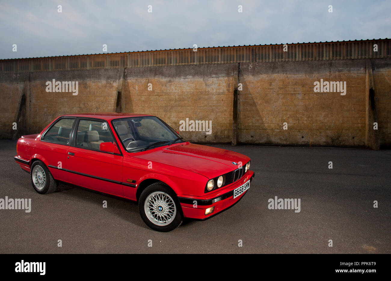 Une droite UK spec 1990 rouge porte 3 BMW E30 série 3 sur une zone industrielle en Angleterre, Royaume-Uni Banque D'Images