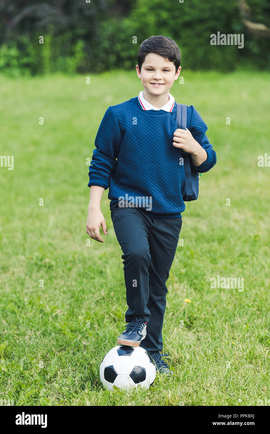 Adorable gamin avec ballon de soccer et sac à dos sur grass field Banque D'Images