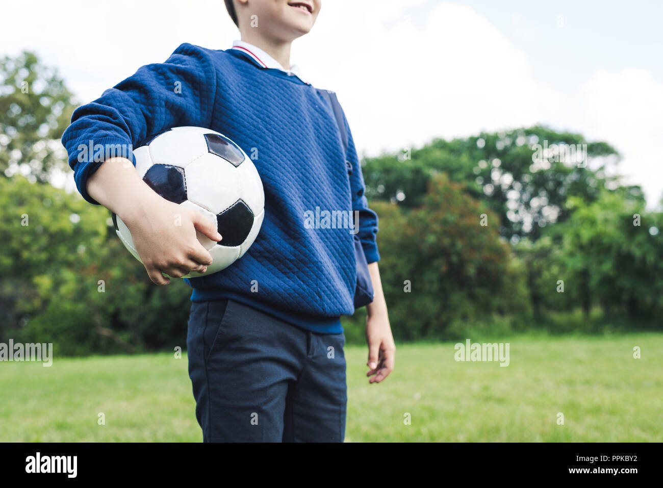 Cropped shot of kid holding soccer ball on grass field Banque D'Images