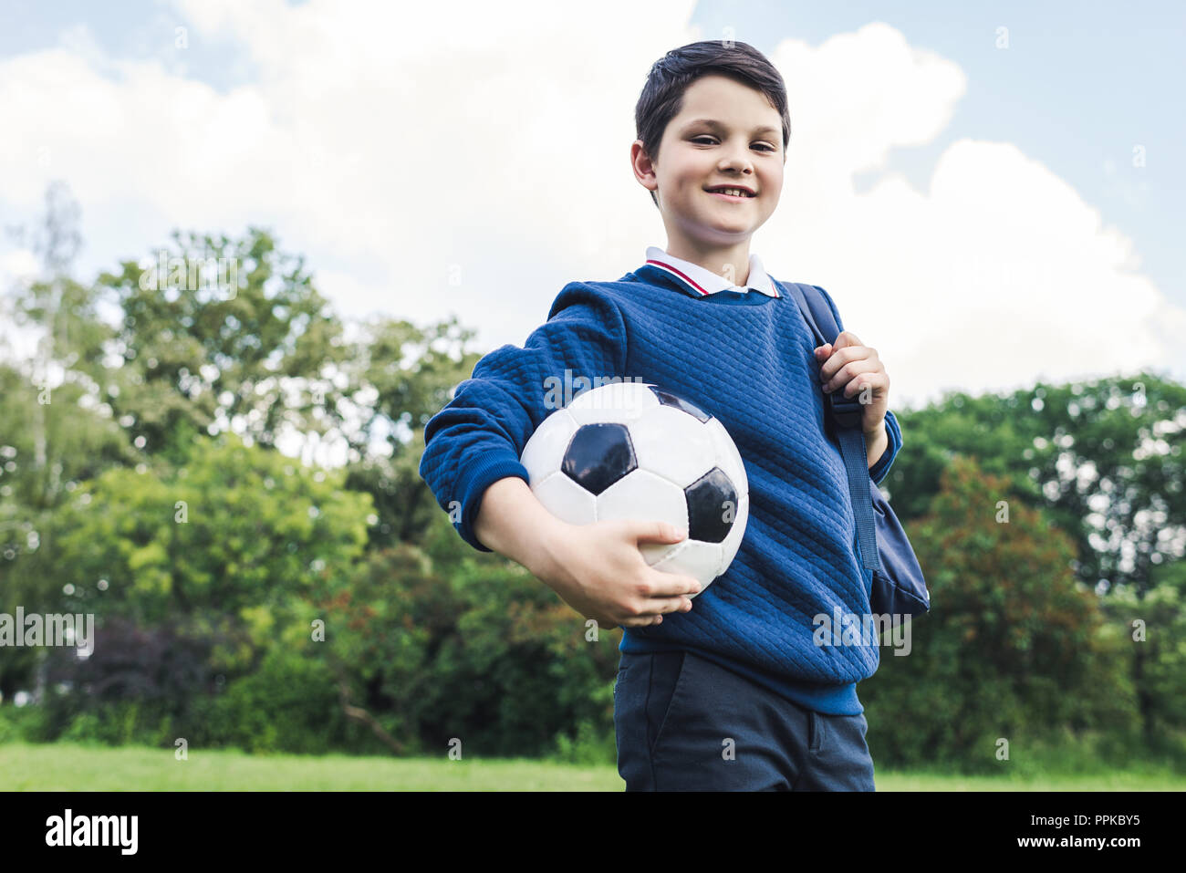 Vue de dessous kid holding soccer ball on grass field Banque D'Images