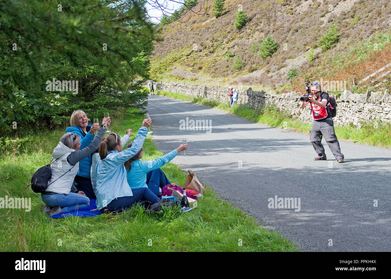Étape 5 Whinlatter Pass Tour d'Angleterre en 2018. Un photographe officiel de la course s'enclenche groupe de femmes bénéficiant du vin mousseux sur la route avant la course. Banque D'Images