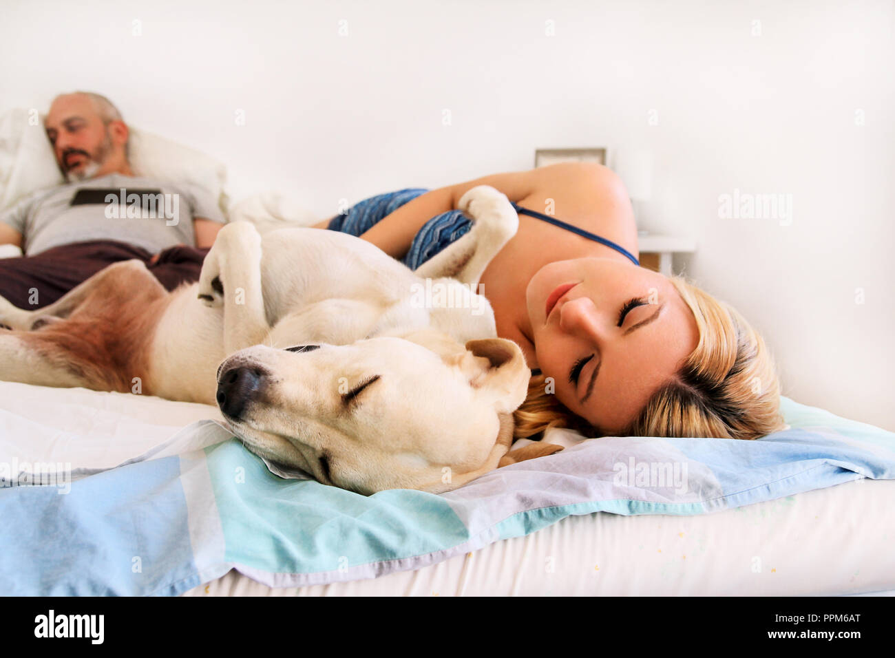 Femme avec des chiens à la maison. Belle femme se reposer et dormir avec  son chien dans le lit dans la chambre à coucher. Propriétaire de chien et  dormir. Concept d'animaux. Labrador