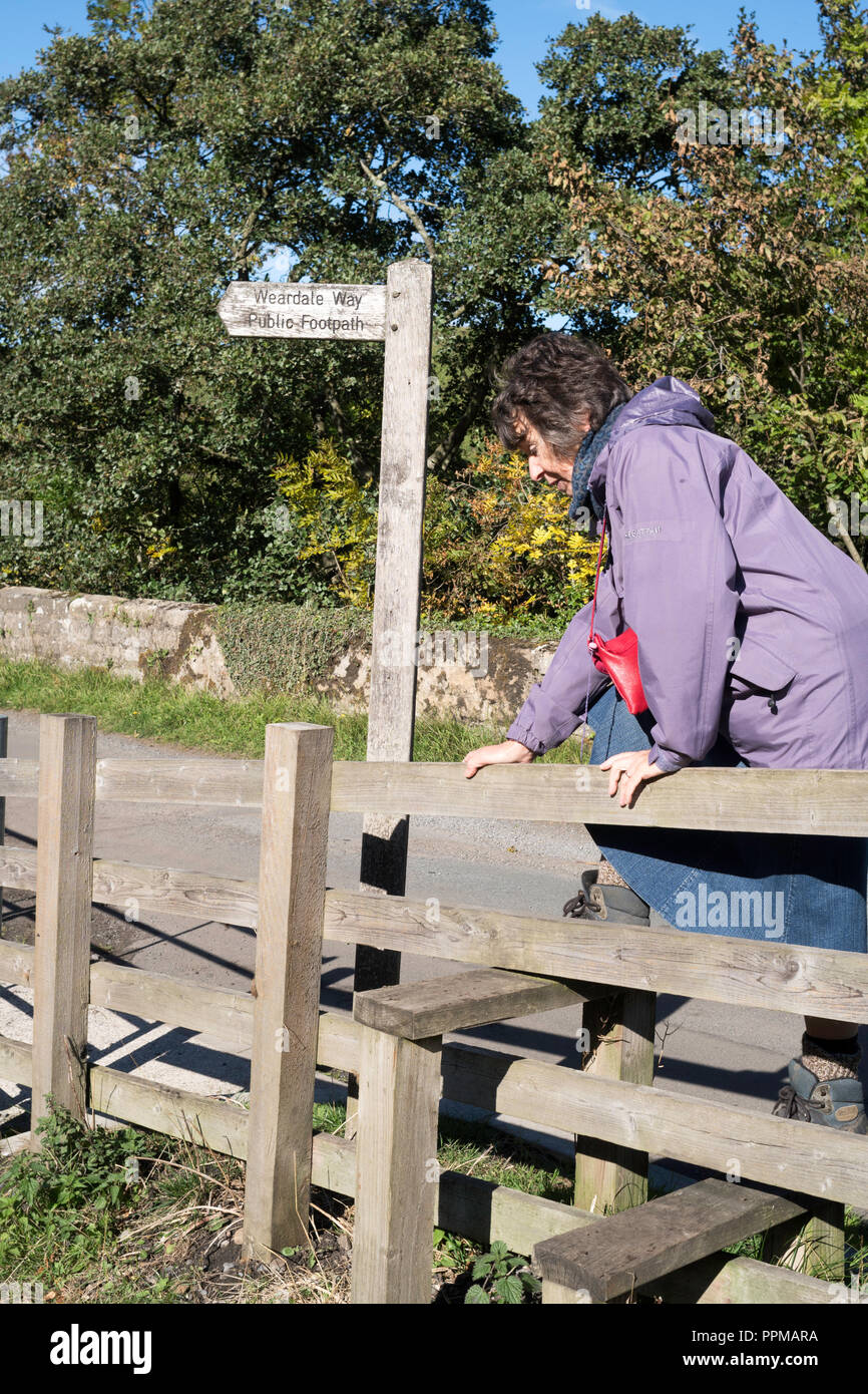 Femme mature la montée au stile sur la façon Weardale, Blanc Kirkley près de Frosterley Co., Durham, England, UK Banque D'Images