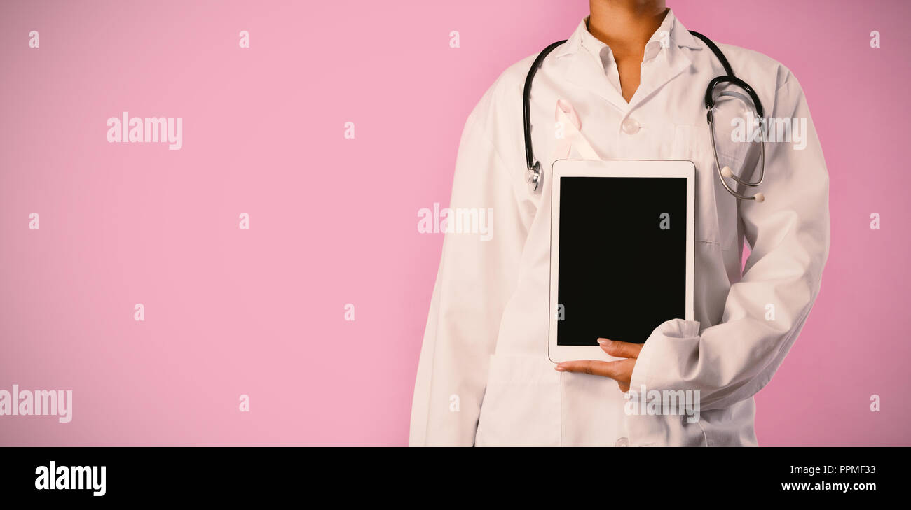 Nurse wearing ruban rose, tenant une tablette dans sa main Banque D'Images