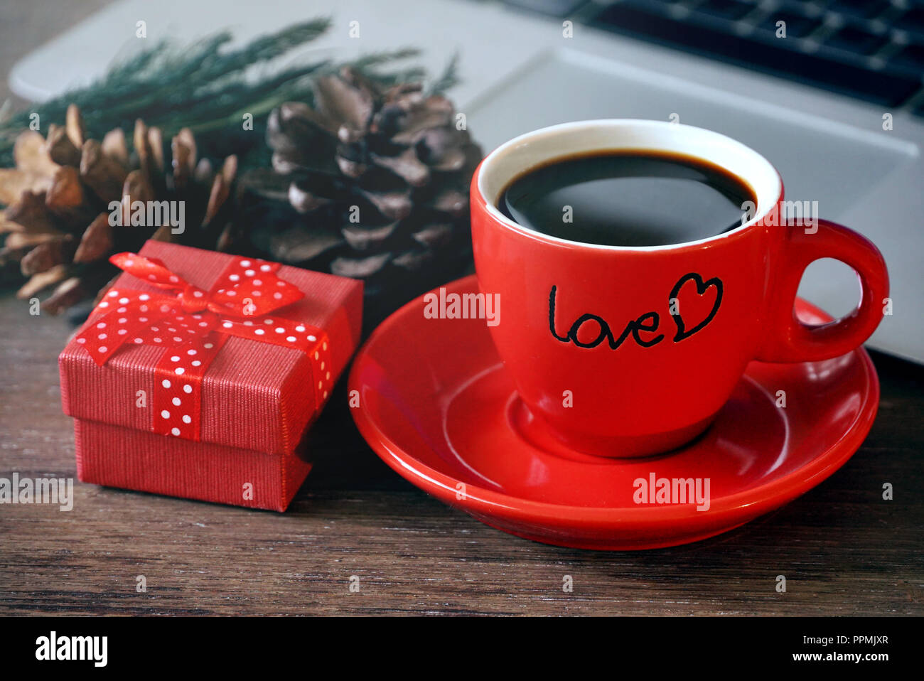 Boîte cadeau rouge et tasse à café expresso décoration avec cône de pin de clavier sur l'arrière-plan. Banque D'Images