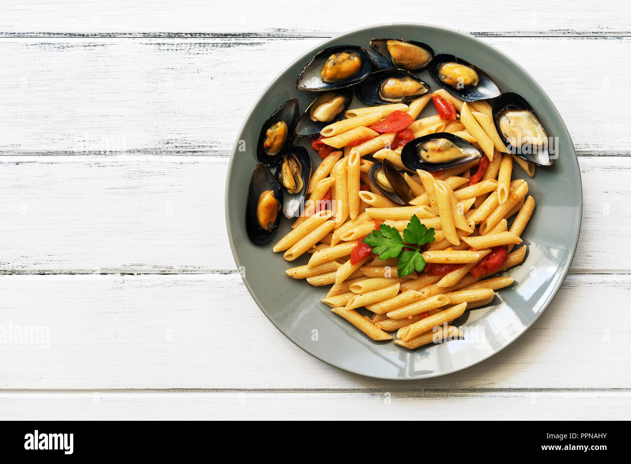 Pâtes penne avec moules sur une table rustique en bois blanc. Vue de dessus, copy space Banque D'Images