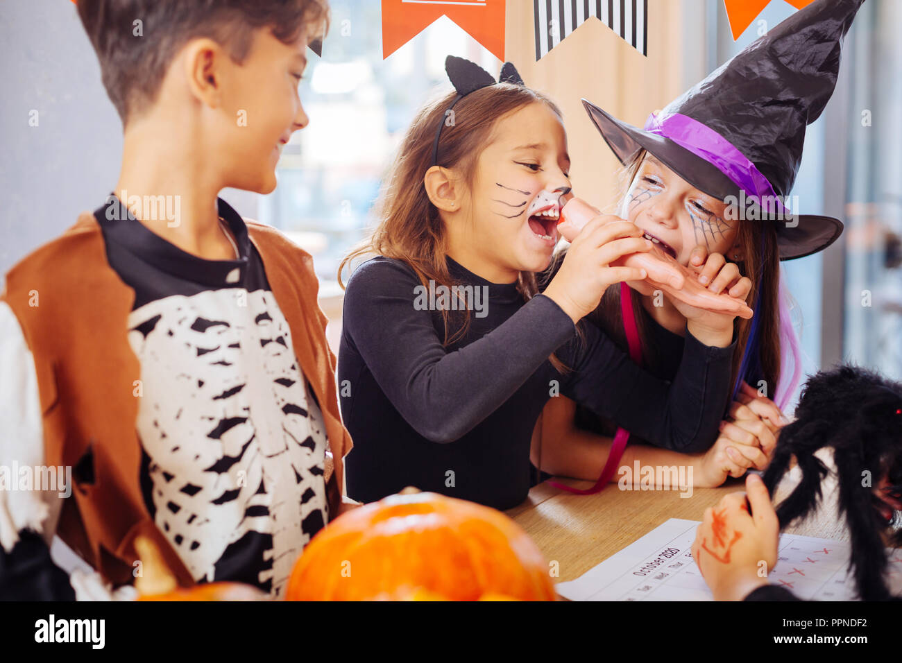 Deux jeunes filles portant des costumes de Halloween essayer main douce cookie Halloween Banque D'Images