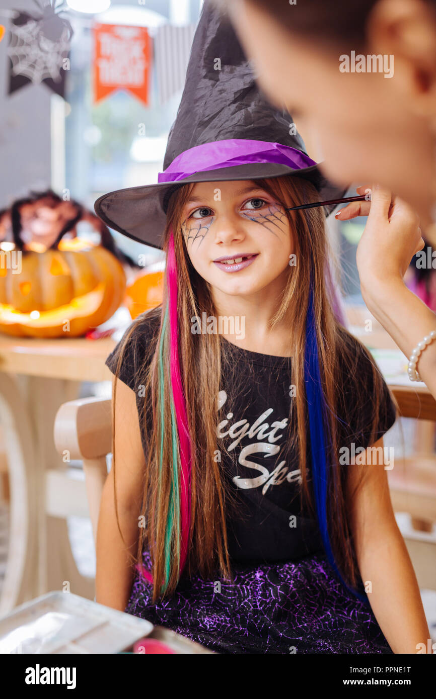 Dark-haired girl wearing hat l'assistant se sentir heureux obtenir maquillage Halloween Banque D'Images