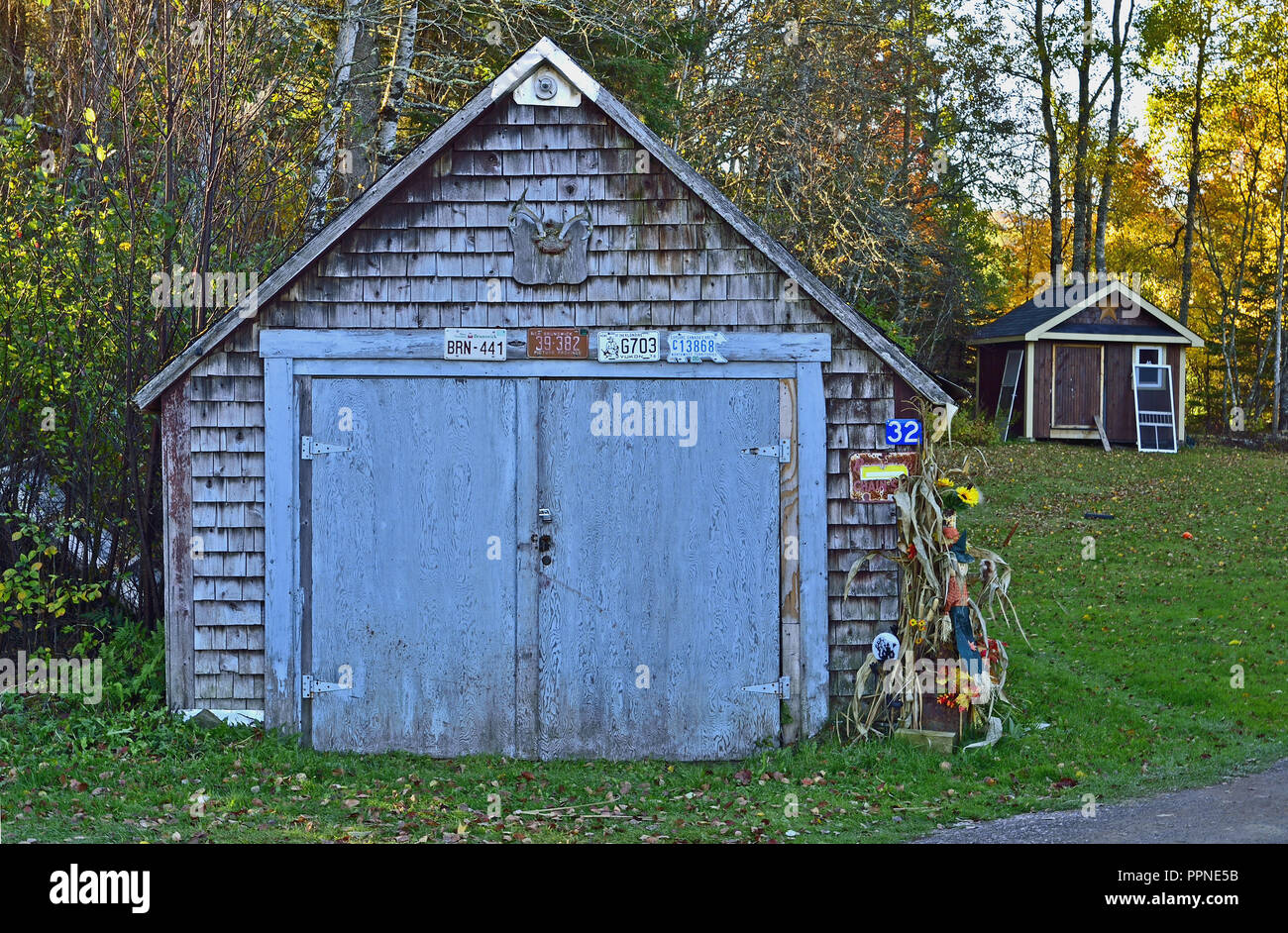 Un vieux bâtiment bleu avec des portes de grange décorée de memorbilia et sert de hangar de stockage ainsi qu'un garage Banque D'Images