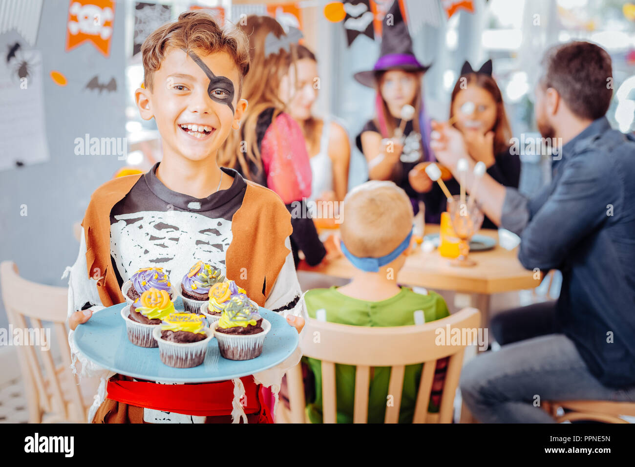 Aux cheveux blonds avec des yeux peints d'écolier portant costume Halloween laughing Banque D'Images