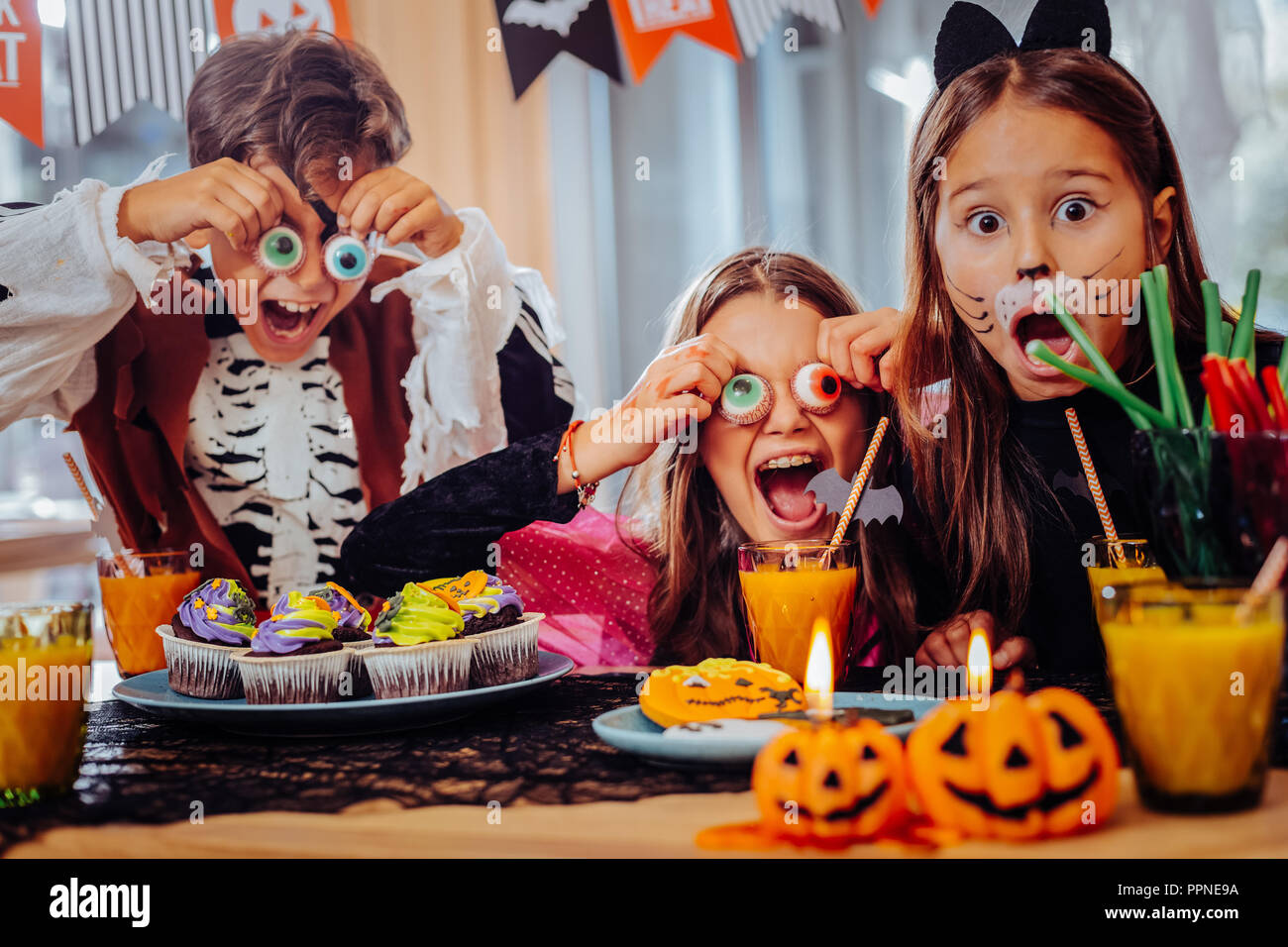Trois écoliers mignon tout en ayant joué des tours avec des bonbons de l'Halloween Banque D'Images