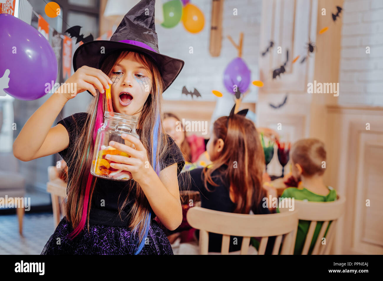 Lycéenne brune portant costume pour Halloween party assistant manger des douceurs Banque D'Images