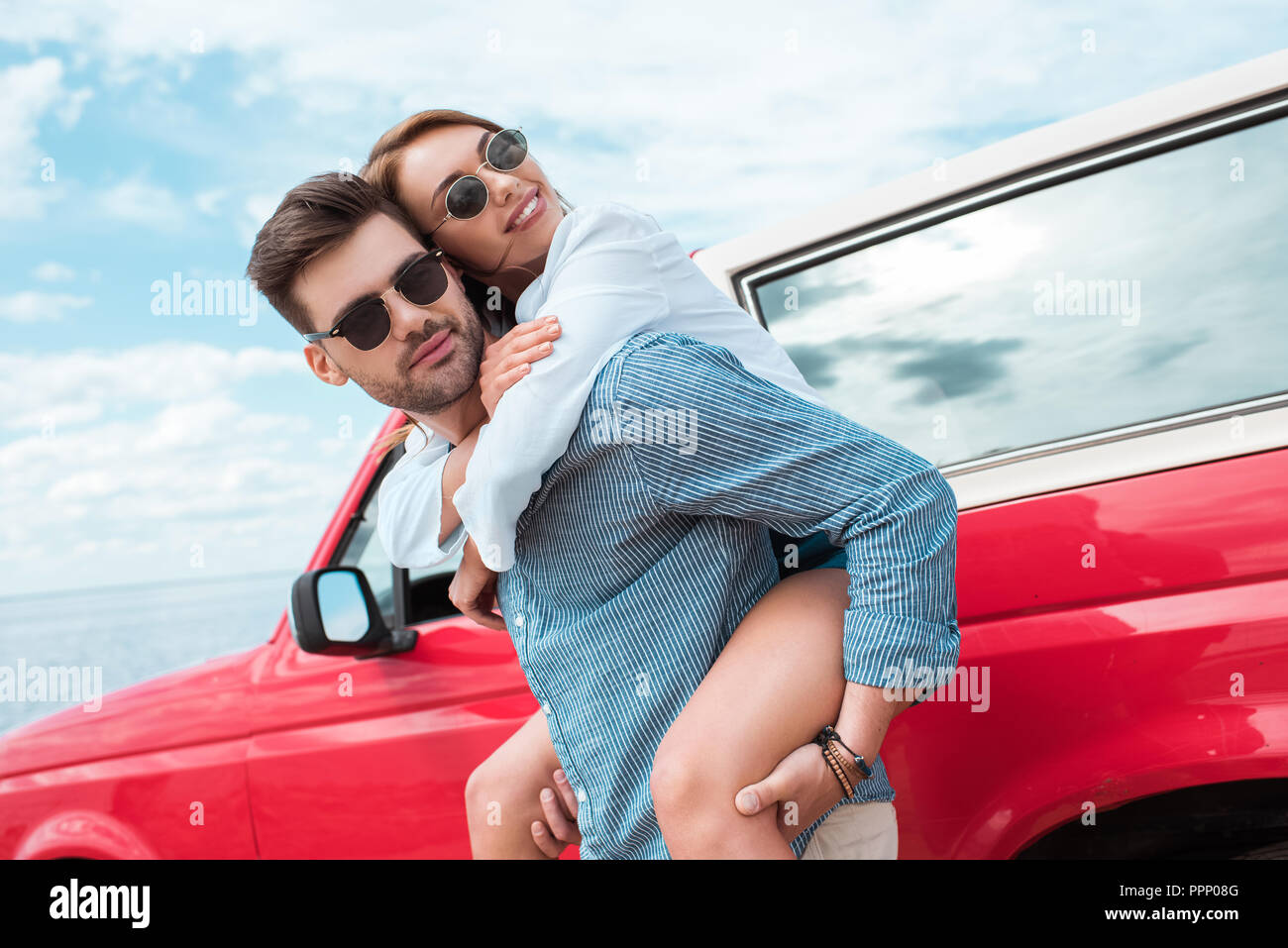 Couple de voyageurs ferroutage près de voiture rouge Banque D'Images