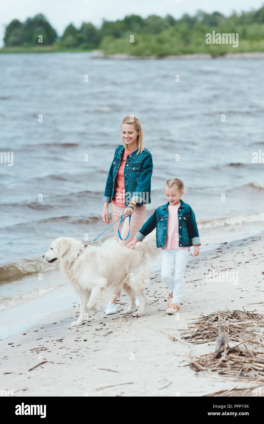 Famille avec golden retriever dog on marche près de la mer Banque D'Images