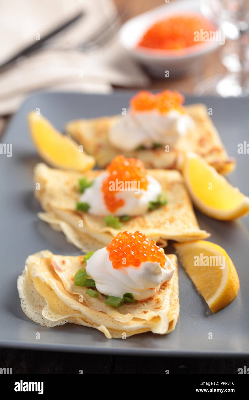 Crêpes avec du caviar rouge sur une plaque Banque D'Images