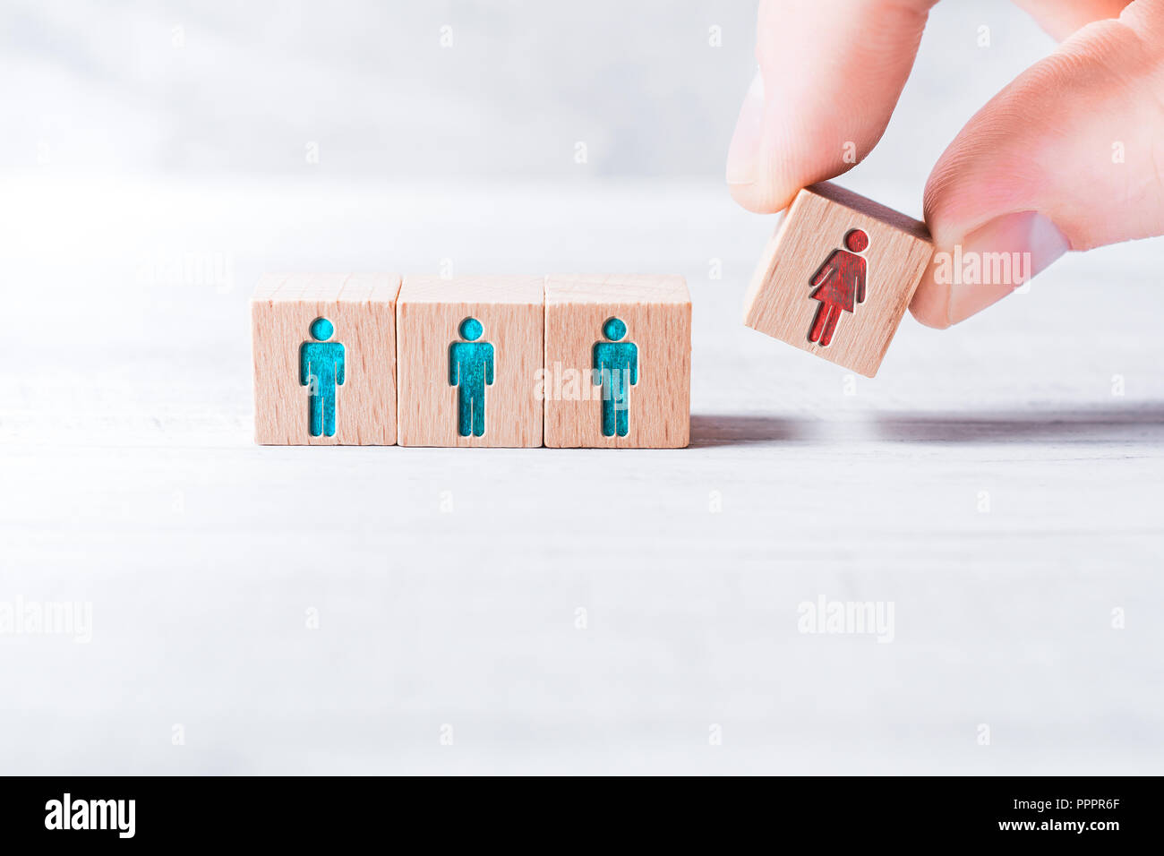 Les doigts masculins de l'ajout d'un bloc avec une femelle de couleur différente à l'icône 3 blocs avec l'égalité homme de couleur des icônes sur un tableau - Concept de l'égalité Banque D'Images