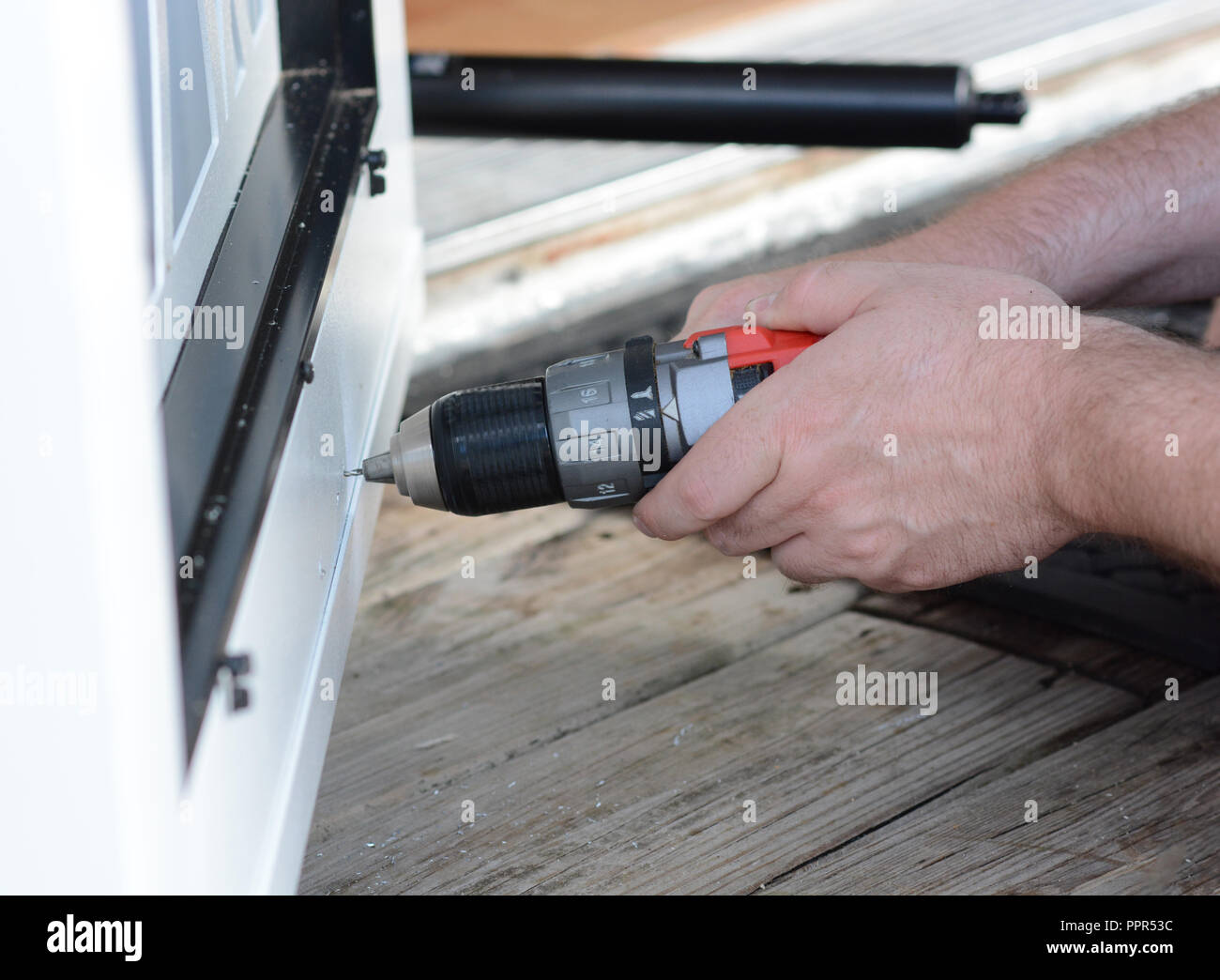 Libre de mains en utilisant un outil électrique pour installer une porte moustiquaire. Banque D'Images