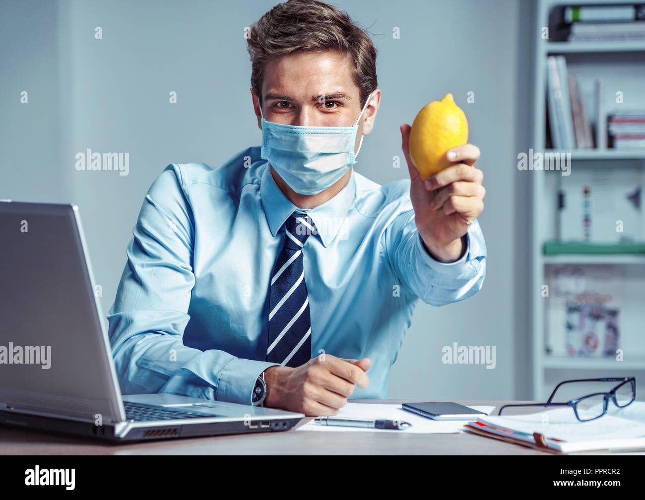 Travailleur en santé au bureau holding citron. Photo d'un homme portant un masque de protection contre les maladies infectieuses et de la grippe. Concept de soins de santé et d'affaires Banque D'Images
