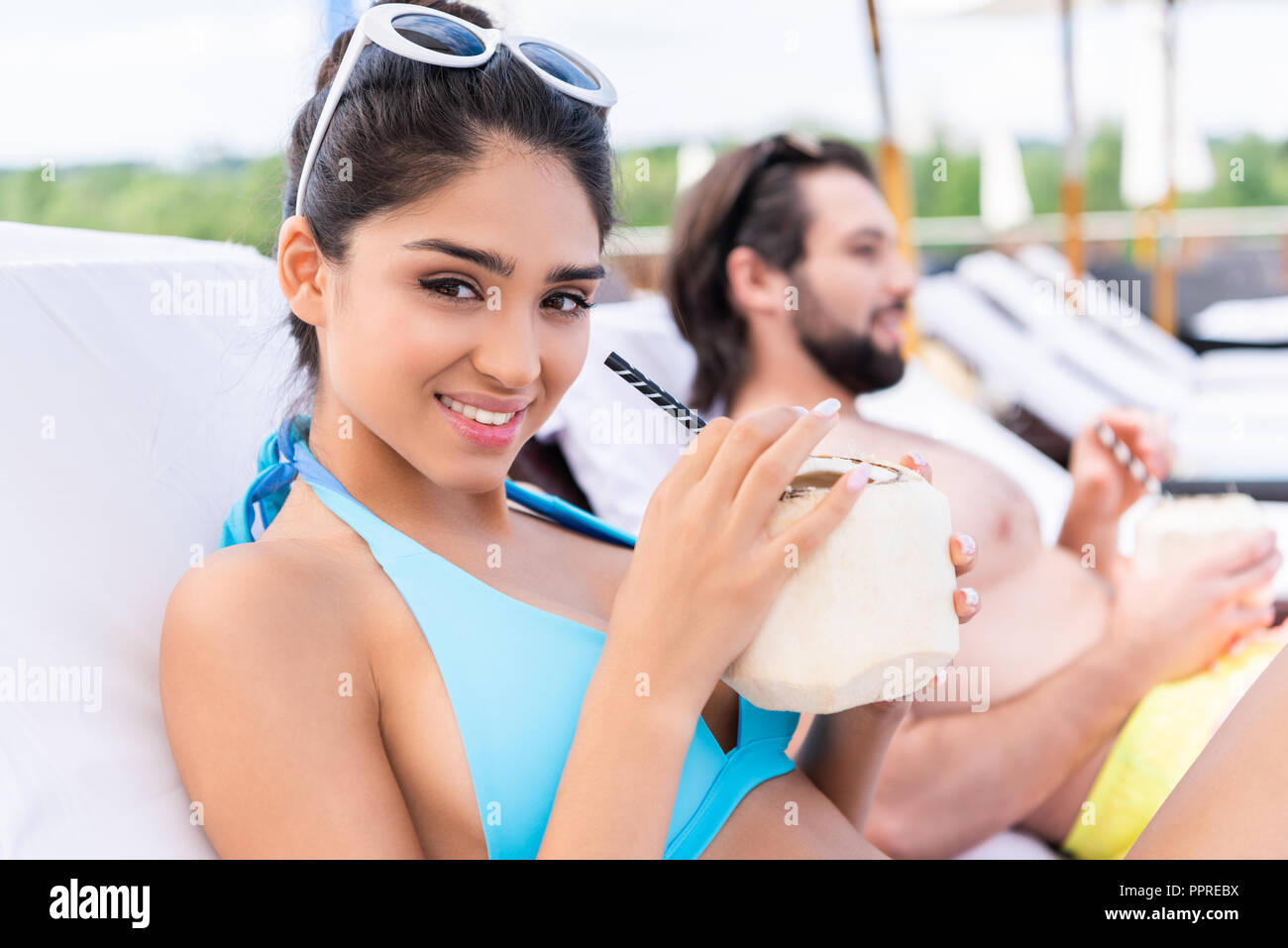 Couple sur les chaises longues avec des cocktails de noix de coco fraîche, selective focus Banque D'Images