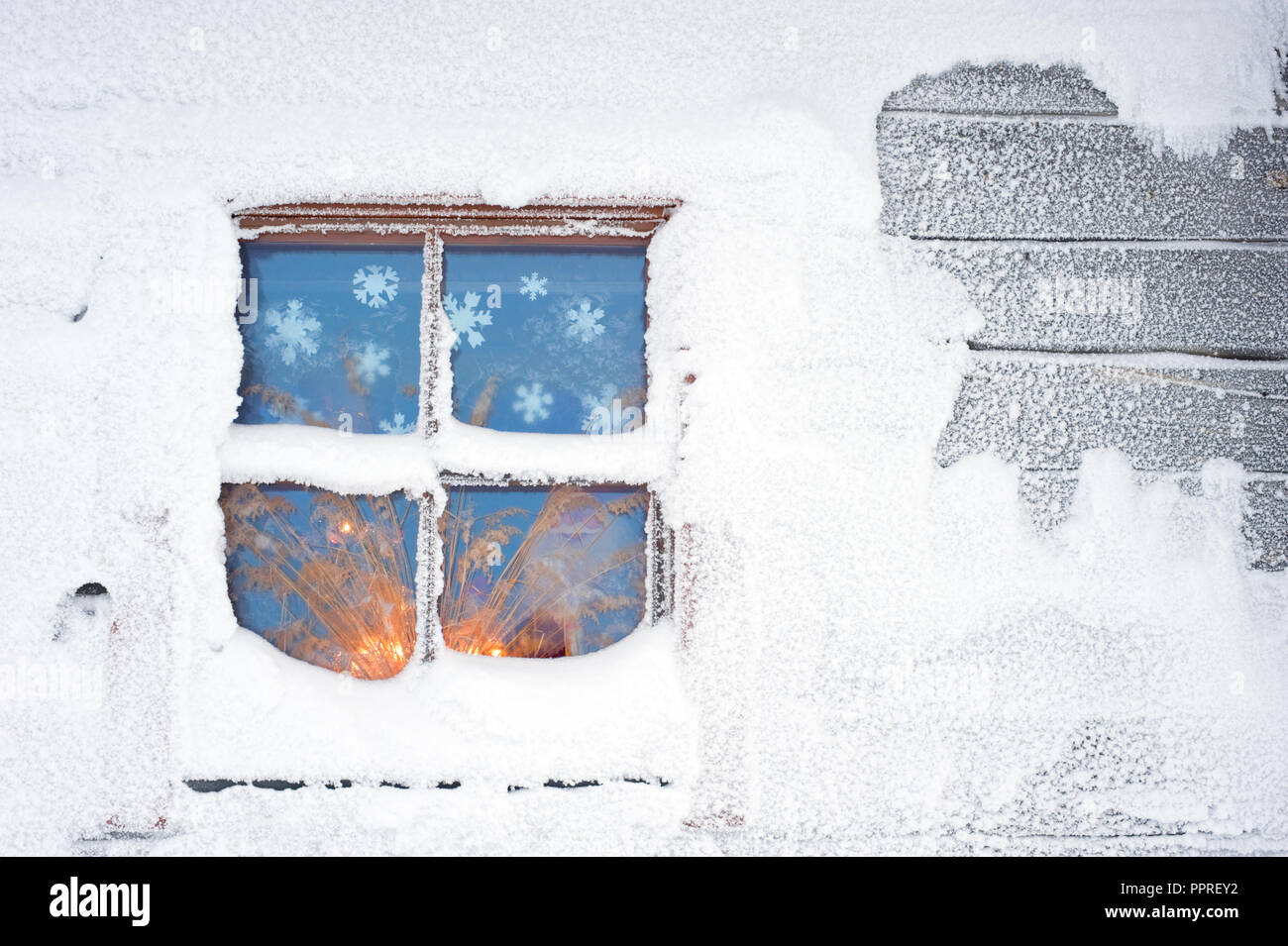 Maison couverte de neige en hiver. Fenêtre givrée par rougeoyant aux chandelles. Banque D'Images