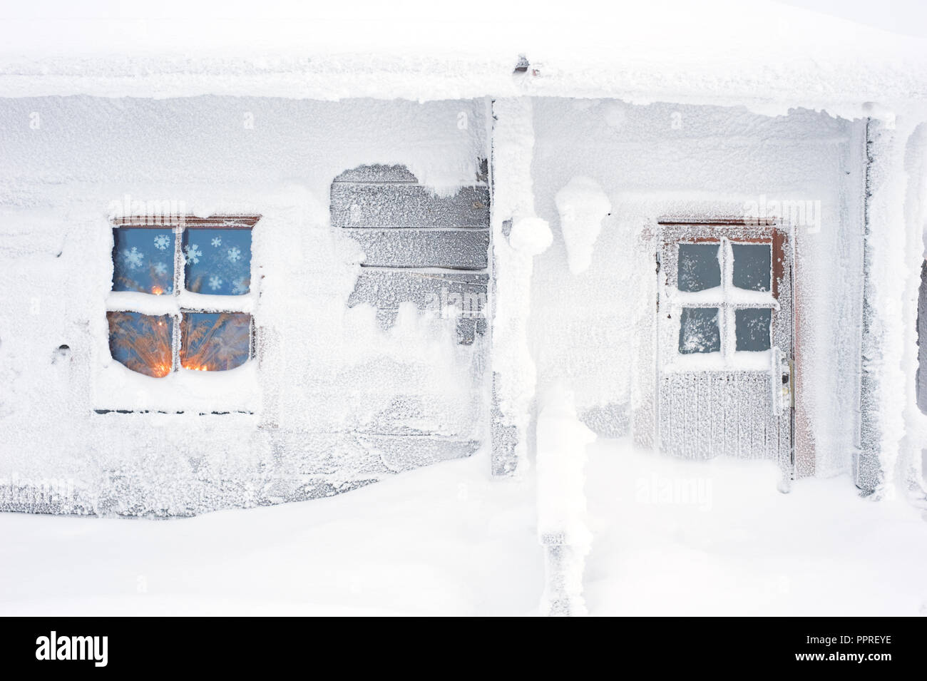 Maison couverte de neige en hiver. Fenêtre givrée par rougeoyant aux chandelles. Banque D'Images