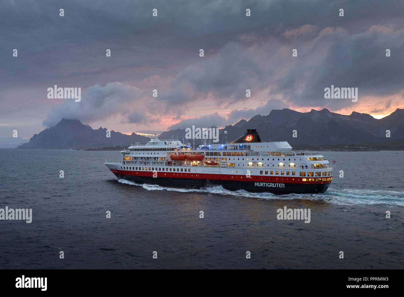 Le ferry Hurtigruten, MS FINNMARKEN, en direction du sud depuis Svolvær. Les montagnes spectaculaires des îles Lofoten et le soleil de minuit derrière la Norvège. Banque D'Images