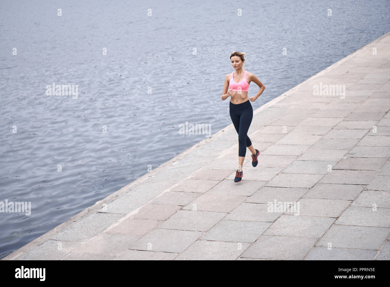 Sérieux au sujet de rester en forme. Vue supérieure de jeunes womanin les vêtements de sport jogging lors de l'exercice en plein air Banque D'Images