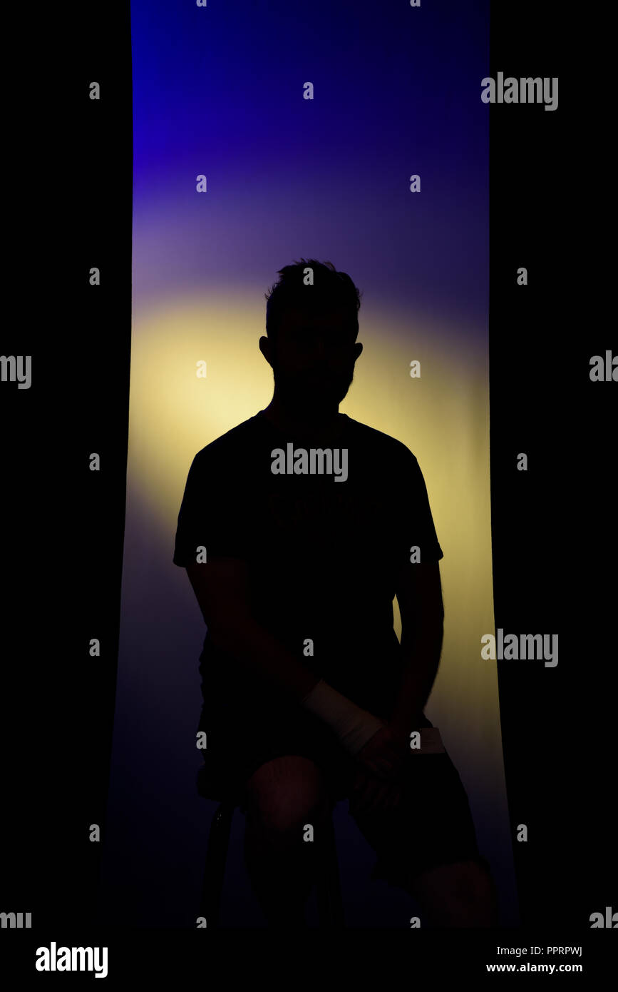 Silhouette d'un jeune homme assis de façon anonyme Banque D'Images