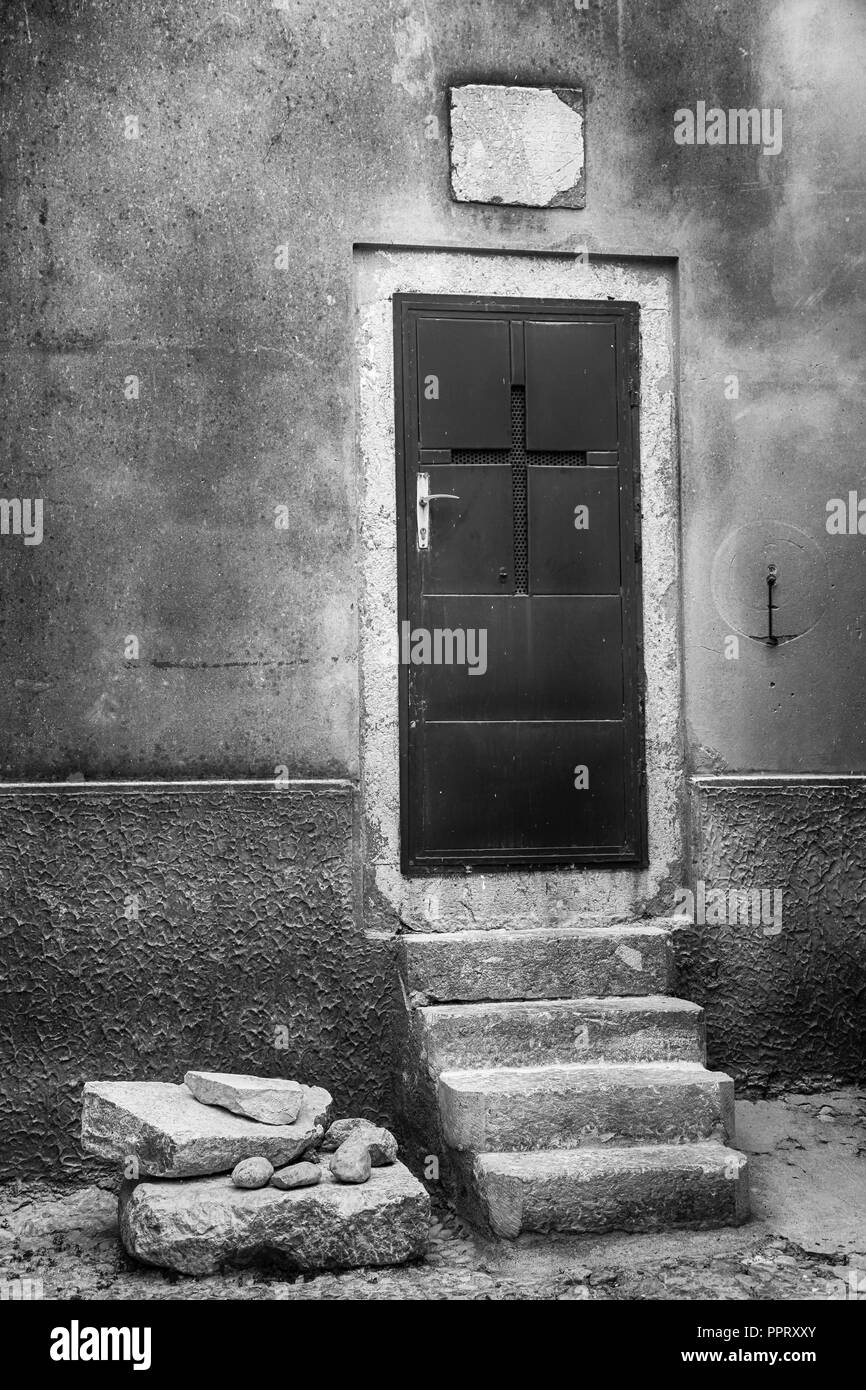 Un rouge rustique porte arrière avec un croisement entre dans une église médiévale de la rues en pierre dans le village médiéval de Vrbnik sur l'île croate de Krk Banque D'Images