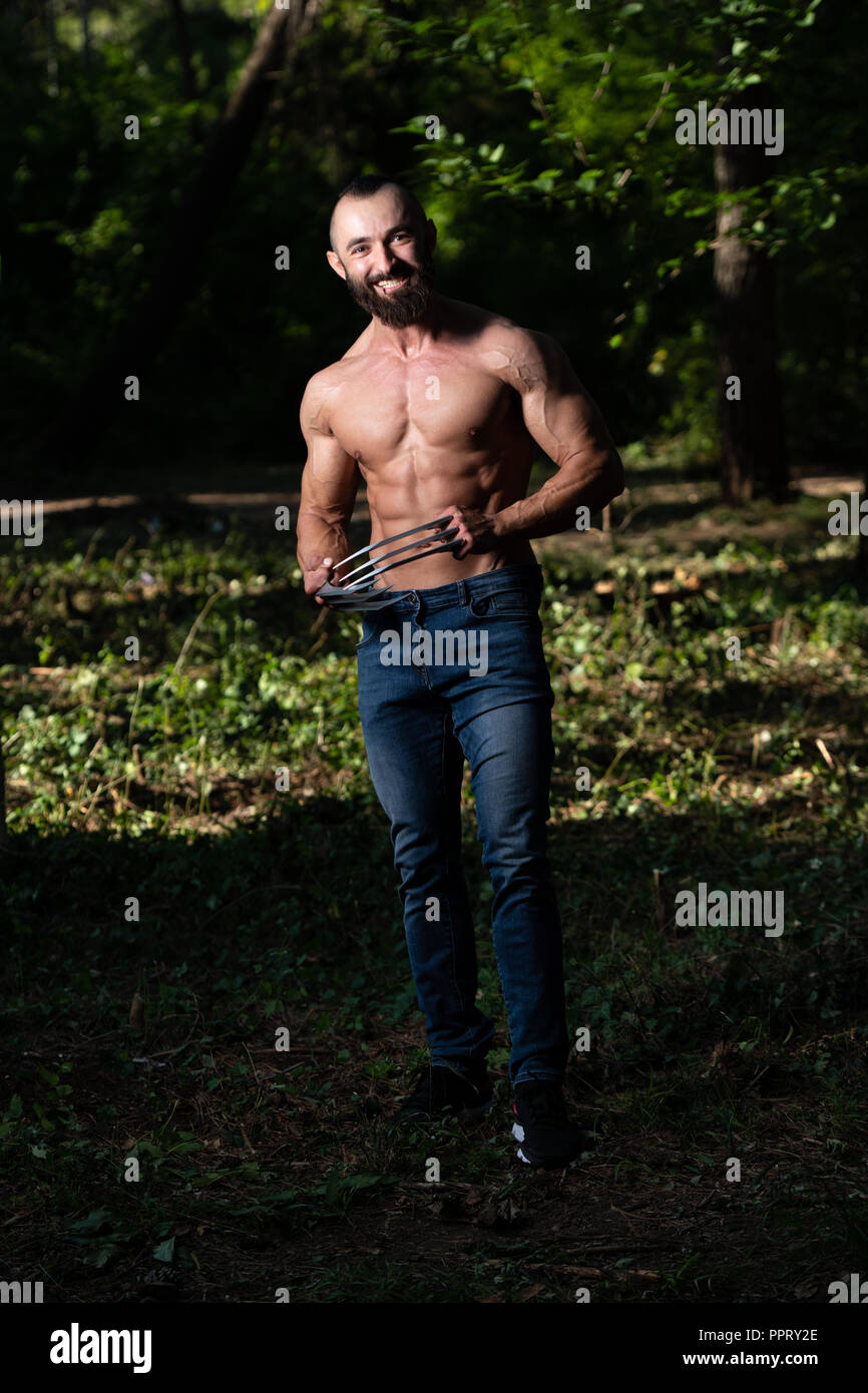 Portrait d'une bonne forme physique avec des griffes de Wolverine montrant son corps bien formé - Remise en forme musculaire Bodybuilder Posing du super-héros athlétiques en plein air Banque D'Images