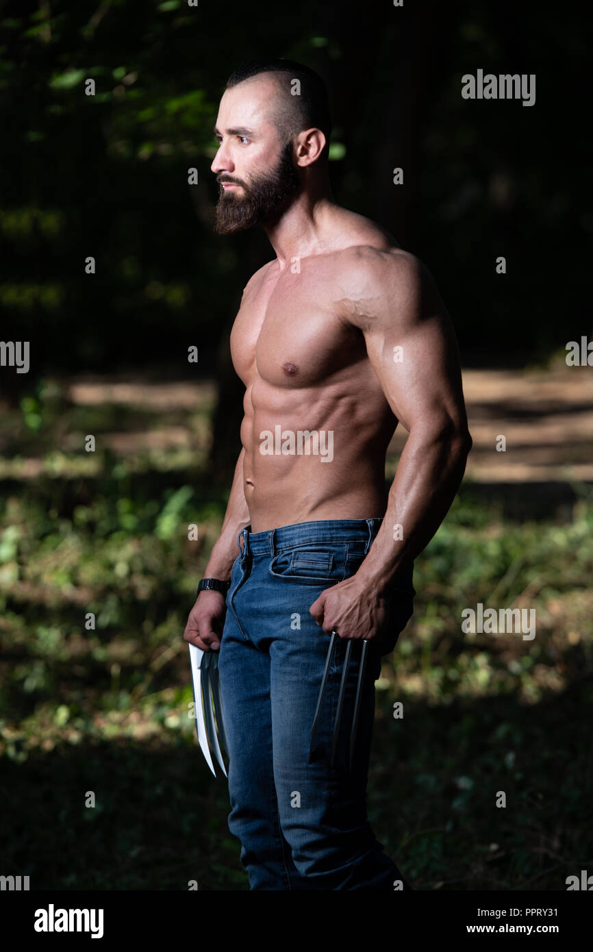 Portrait d'une bonne forme physique avec des griffes de Wolverine montrant son corps bien formé - Remise en forme musculaire Bodybuilder Posing du super-héros athlétiques en plein air Banque D'Images