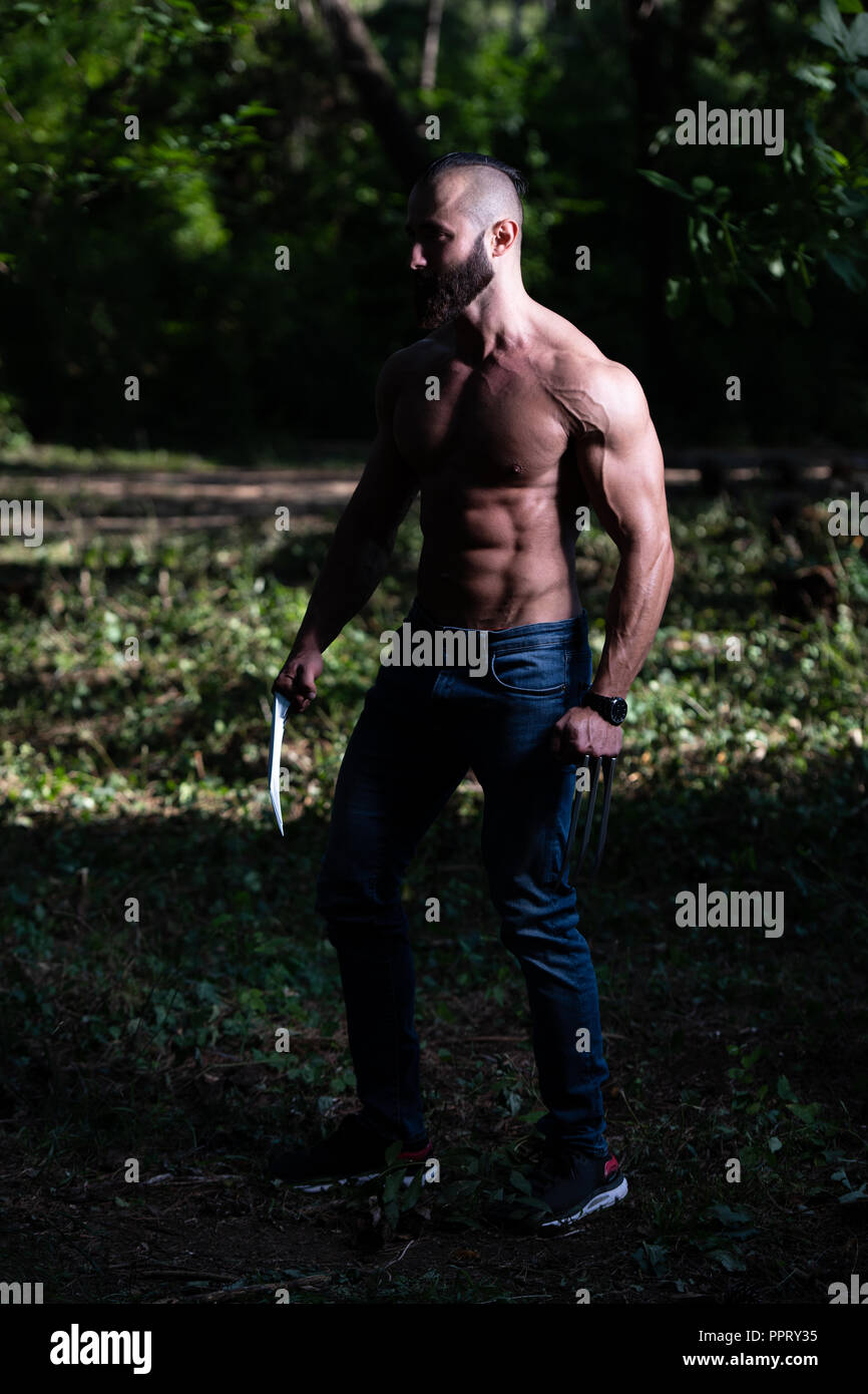 Portrait d'une bonne forme physique avec des griffes de Wolverine montrant son corps bien formé - Remise en forme musculaire Bodybuilder Posing du super-héros athlétiques en plein air Banque D'Images