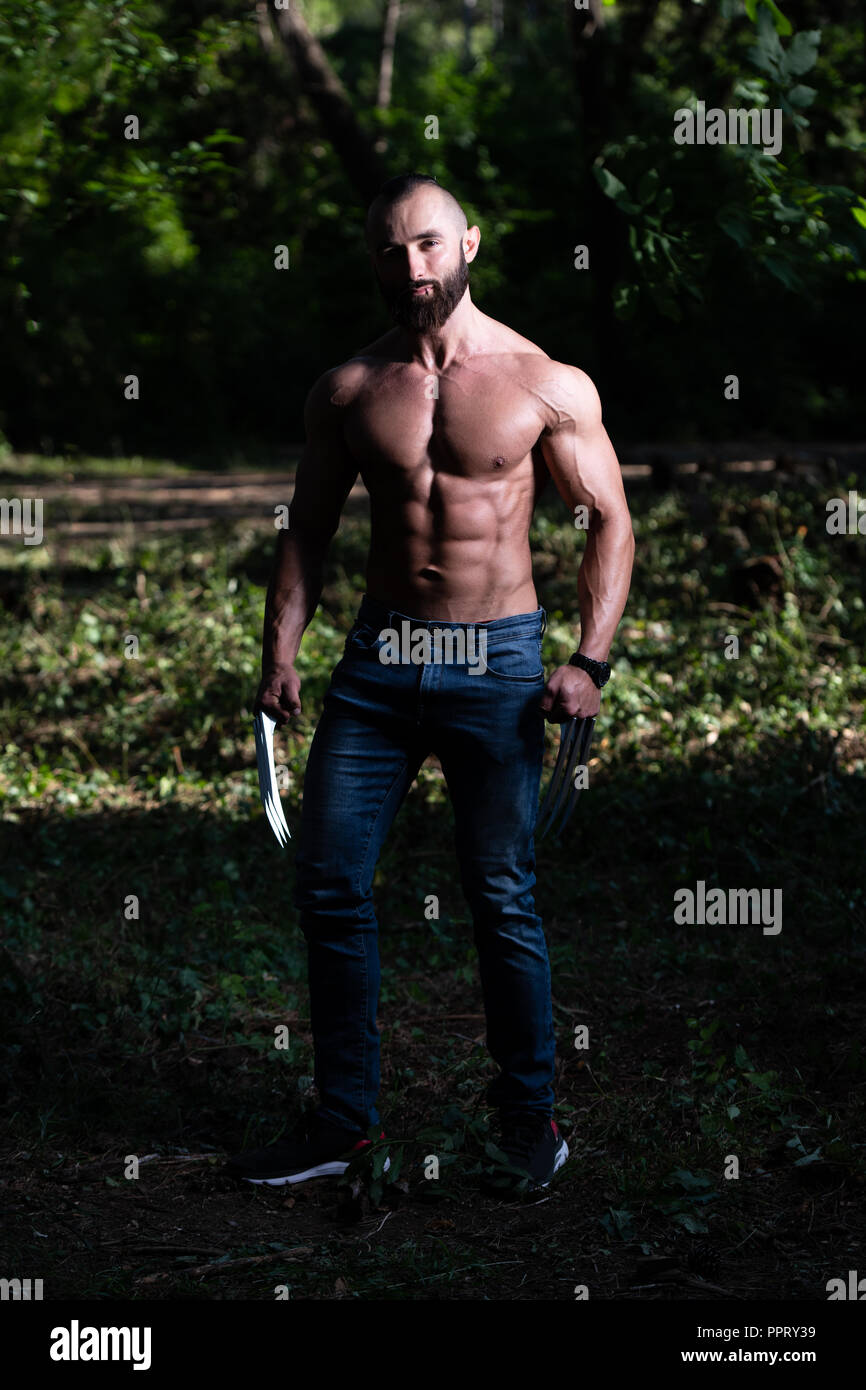 Avec des griffes de superhero Standing Strong Flexing Muscles - Athletic musculaire Fitness Bodybuilder Posing Outdoors Wolverine Banque D'Images